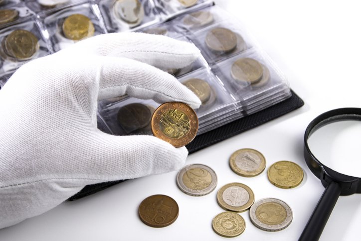 A collector in white gloves examines a coin, close-up, a customer wanted to sell.